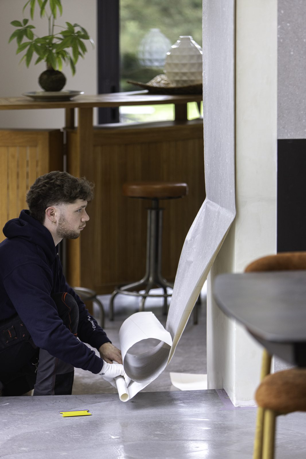 Instalador retirando el papel de protección mientras el vinil sube por la columna